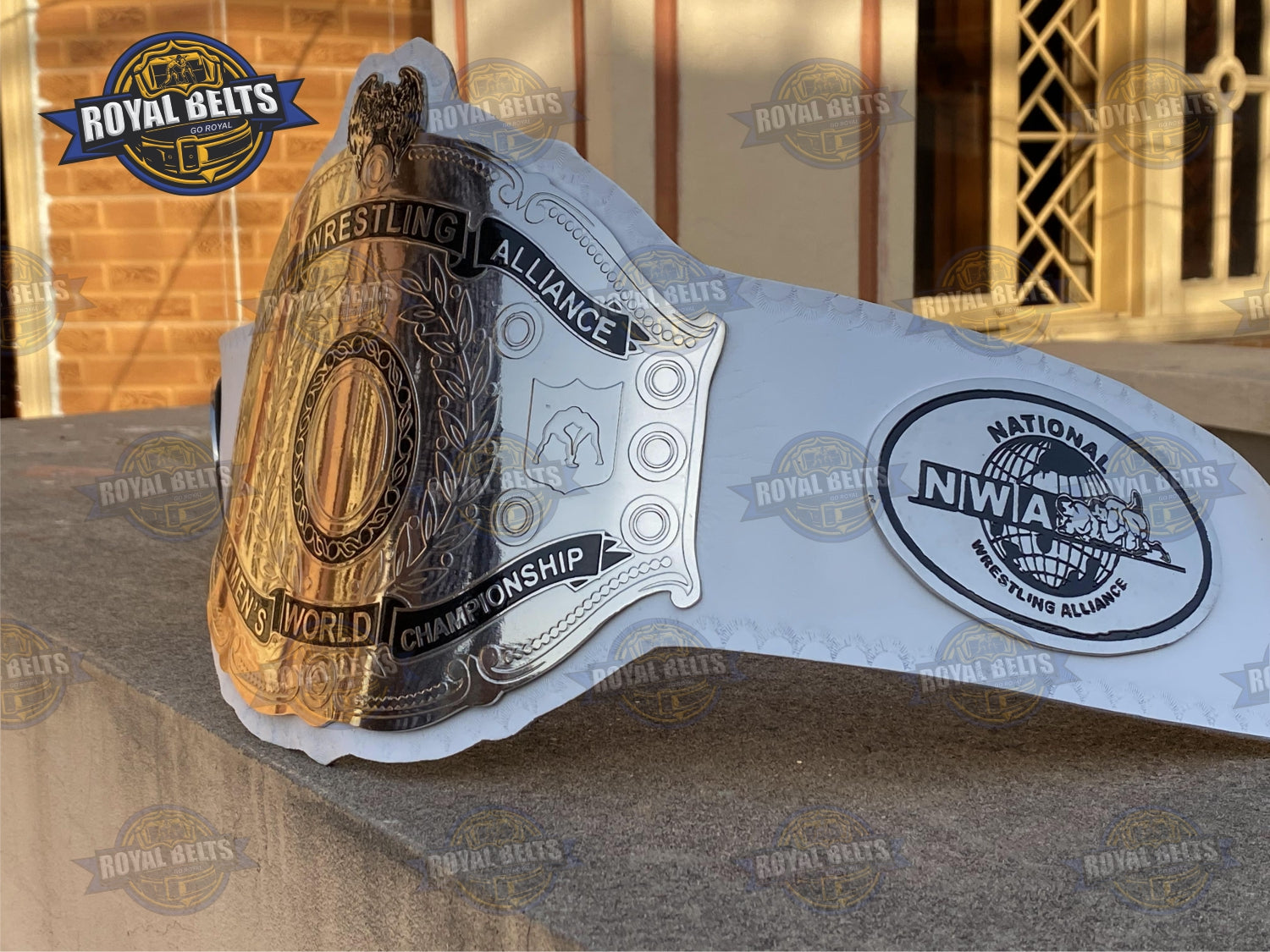 NWA Women’s Championship Belt featuring polished brass engraved plates, smooth white leather strap