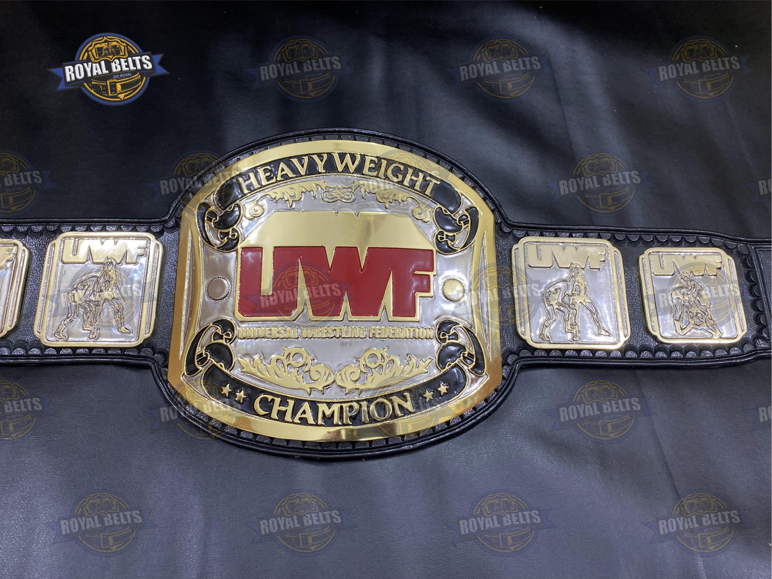 UWF belt with oversized center plate, mirror polished gold finish, detailed side plates, black leather strap