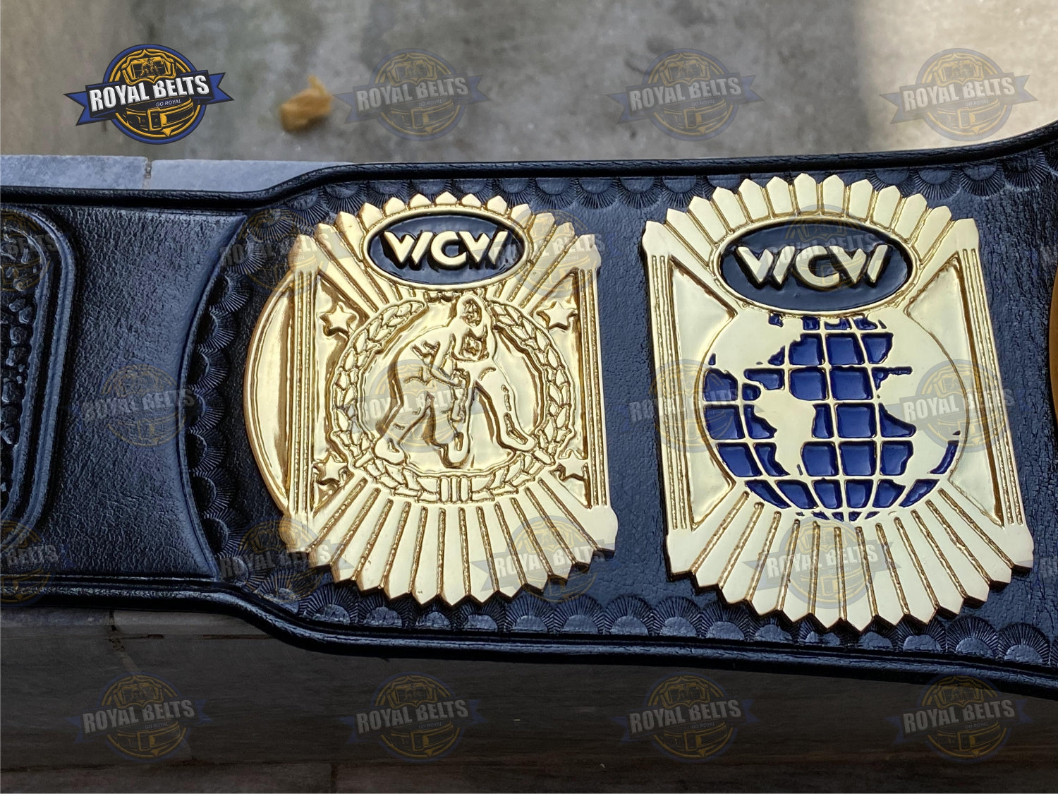Custom WCW belt displaying bold embossed center plate, thick metal construction, stitched black leather strap